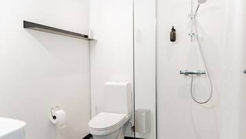 Un baño moderno con inodoro, ducha y dispensador de papel higiénico.