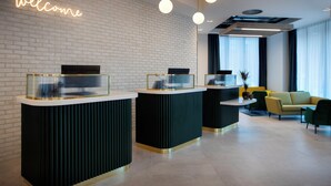 A modern reception area with a 'welcome' sign, three reception desks, a sofa, and a coffee table. - Leonardo Hotel Bristol City (Bristol)