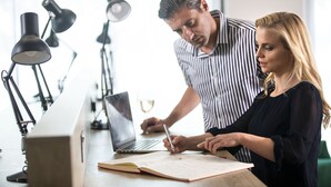 A person writing in a notebook with a laptop on a desk, surrounded by multiple desk lamps. - Leonardo Hotel Bristol City (Bristol)