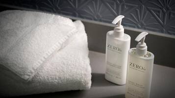 A bathroom with a white towel and two bottles of ZERO% hand wash.