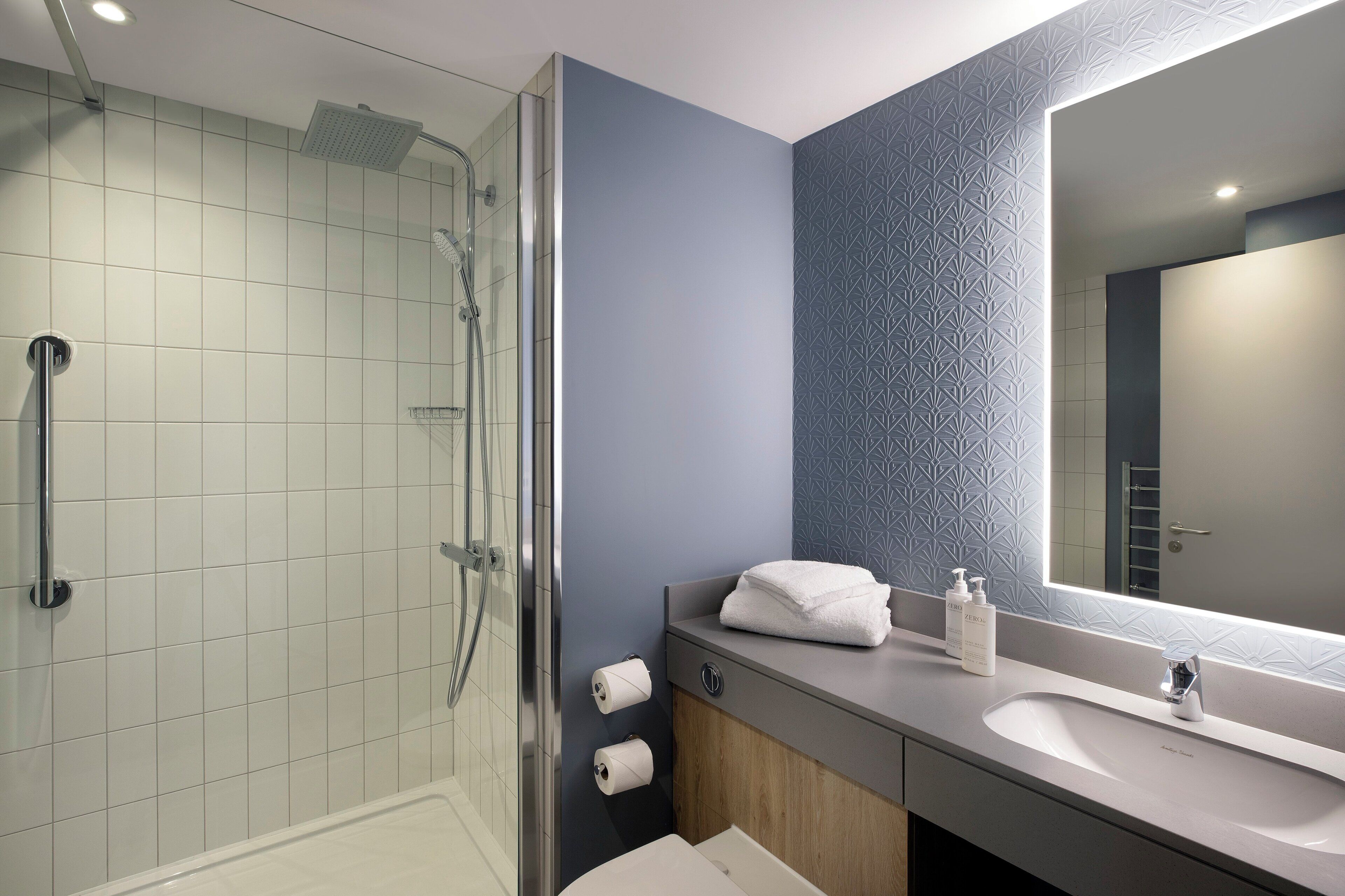 A modern bathroom with a glass shower enclosure, a vanity with a mirror, and a sink.