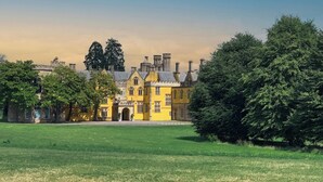 A large, historic building with a yellow facade, surrounded by lush green lawns and trees. - Leonardo Hotel Bristol City (Bristol)