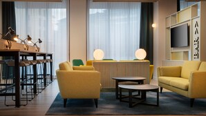 A modern hotel lobby with a bar area, seating, and a large TV screen. - Leonardo Hotel Bristol City (Bristol)