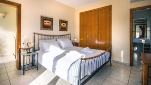 Quarto bem iluminado com uma cama grande, guarda-roupa de madeira e duas molduras na parede.