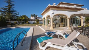 Uma área de piscina com espreguiçadeiras e um terraço coberto.