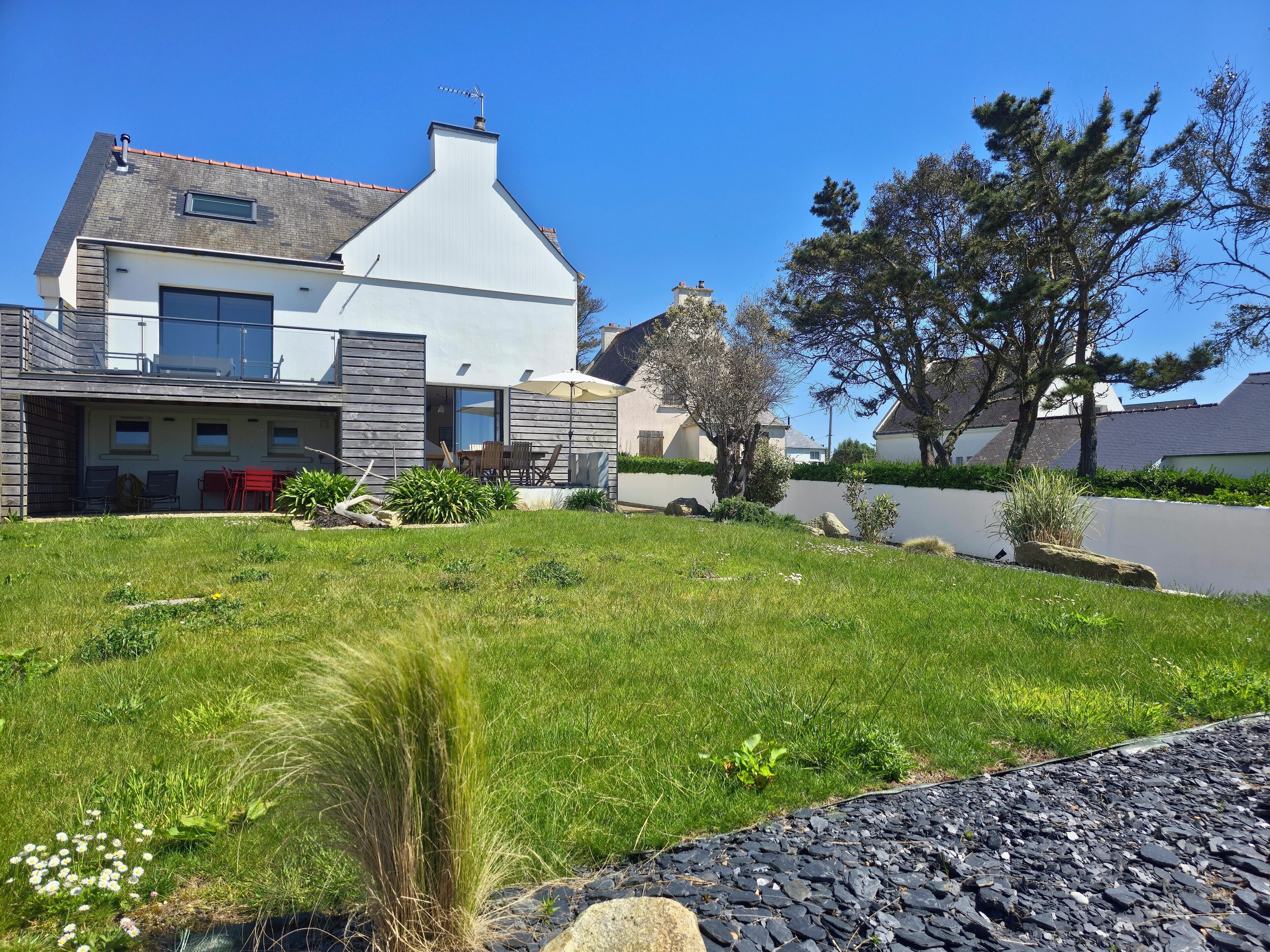 A modern two-story house with a large front yard, a covered patio, and a driveway.