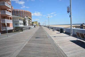 A wooden boardwalk leading to a beach with buildings on one side. - Cute, relaxing 1-bedroom oceanfront condo located directly on the Boardwalk with free WiFi and a stunning ocean view! (Ocean City)