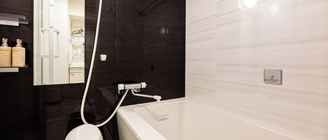 A modern bathroom with a bathtub, a toilet, and a shower area.