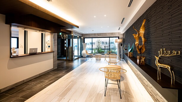 Een moderne lobby met een receptiebalie, een zithoek en een groot raam met uitzicht op de stad.