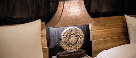 A neatly made bed with a wooden headboard, a decorative wall hanging, and a lamp on a bedside table.