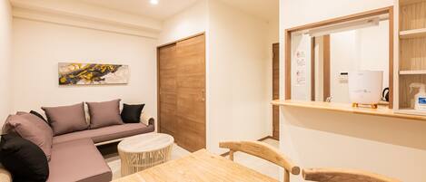 A modern living room with a sofa, a round table, and a wooden chair.