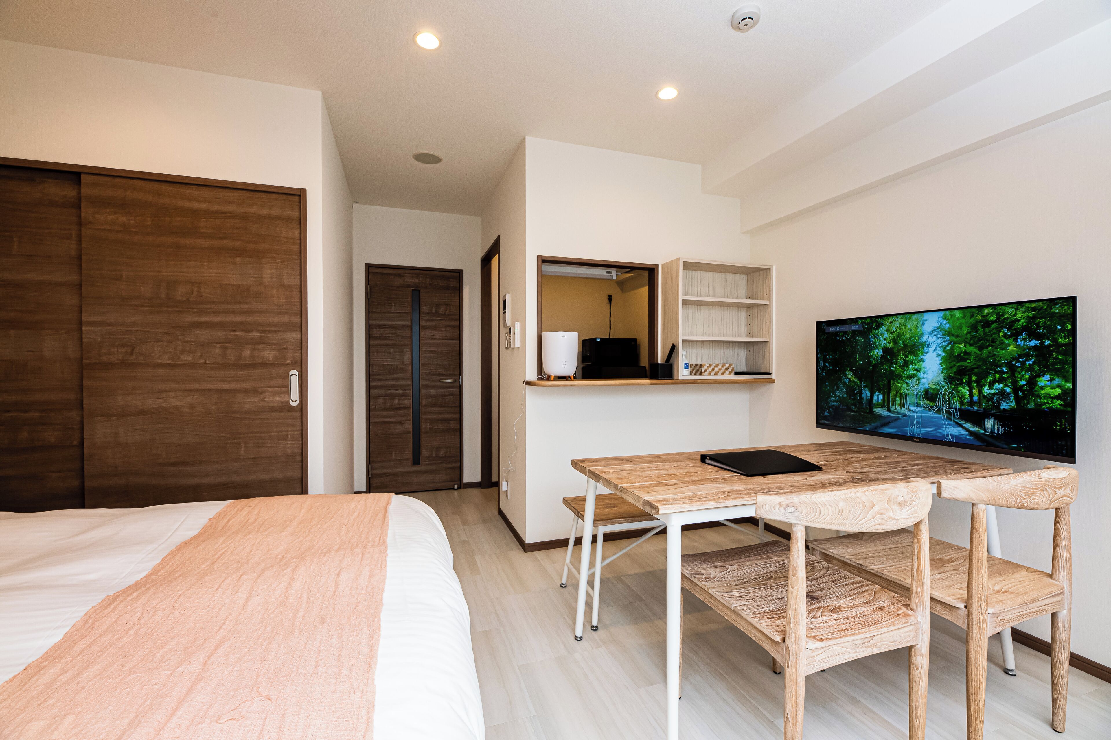 Een moderne hotelkamer met een bed, een bureau met stoel, een televisie en een kledingkast.