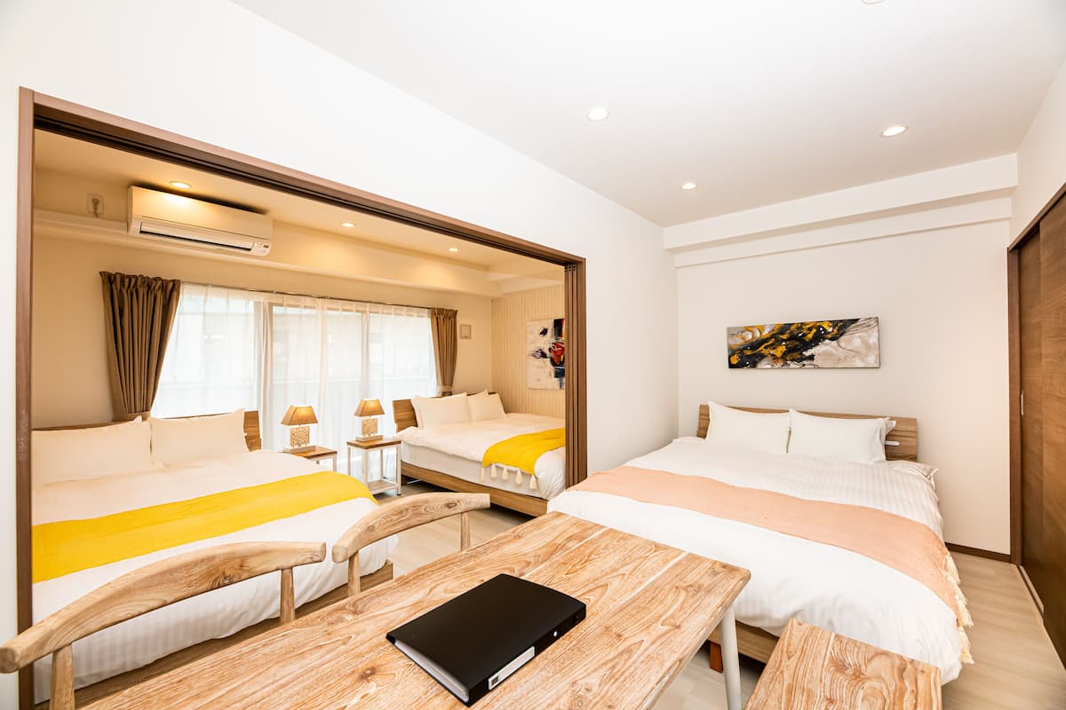 A hotel room with two beds, a wooden desk, a mirror, and a painting on the wall.