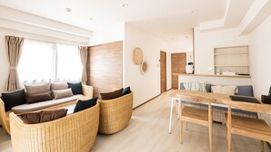 Een moderne woonkamer met een zithoek, een eettafel en een keuken op de achtergrond.