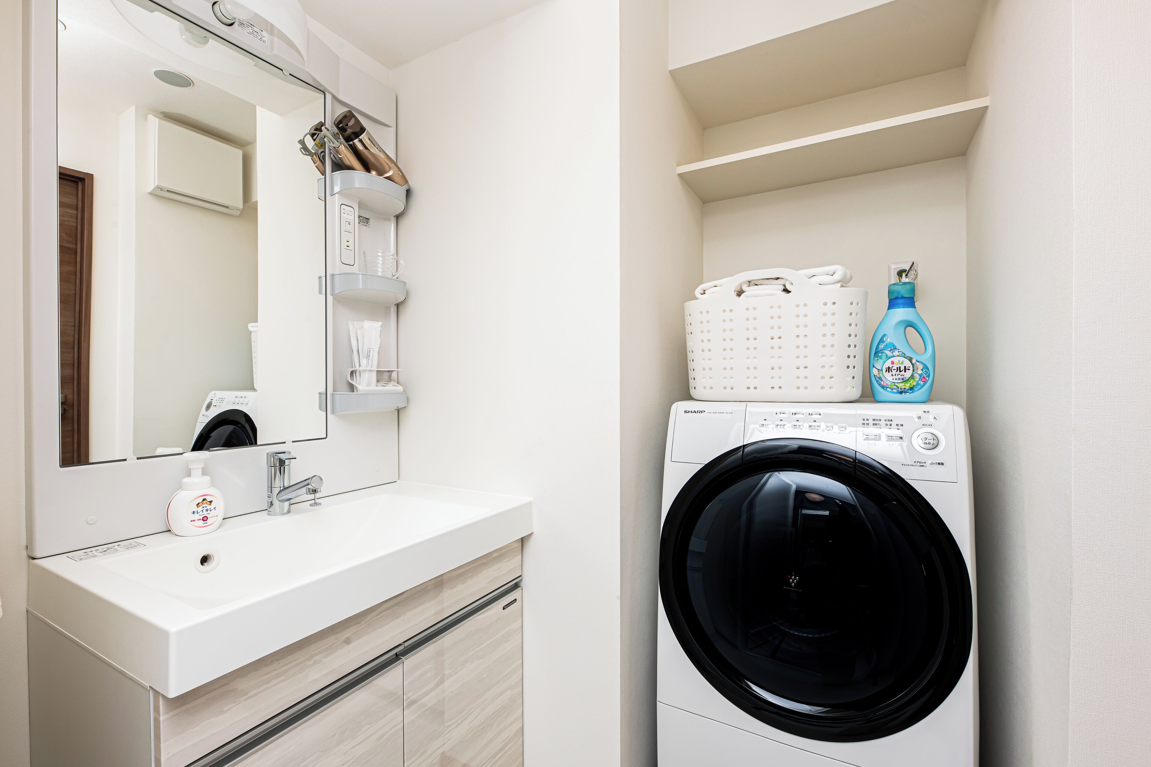A modern bathroom with a white sink, mirror, and a washing machine.