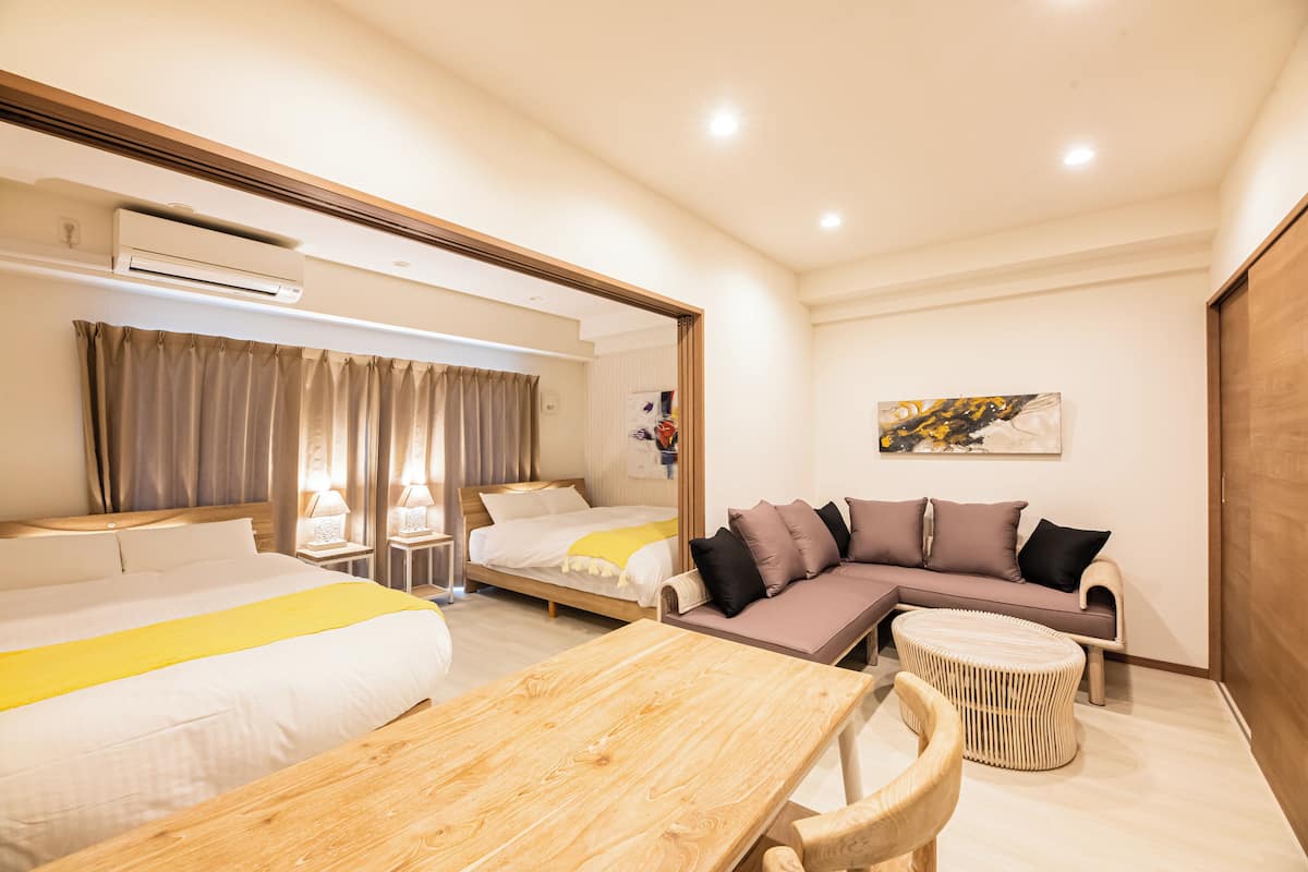 A hotel room with a bed, a sofa, a wooden table, and a small round table.