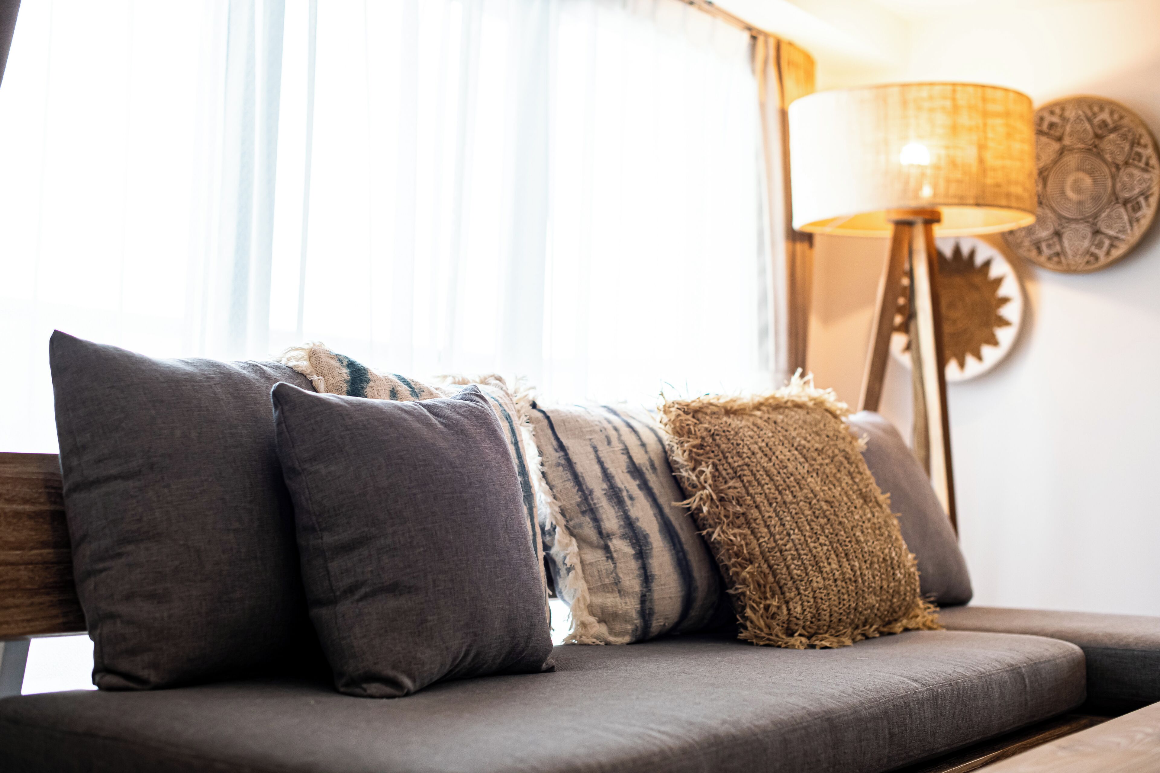 Un canapé agrémenté de plusieurs coussins, une lampe et des assiettes décoratives accrochées au mur.