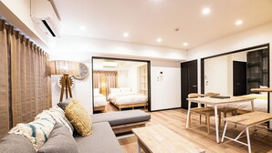 Een moderne hotelkamer met een bank, een houten tafel en een bed met uitzicht op een andere kamer.