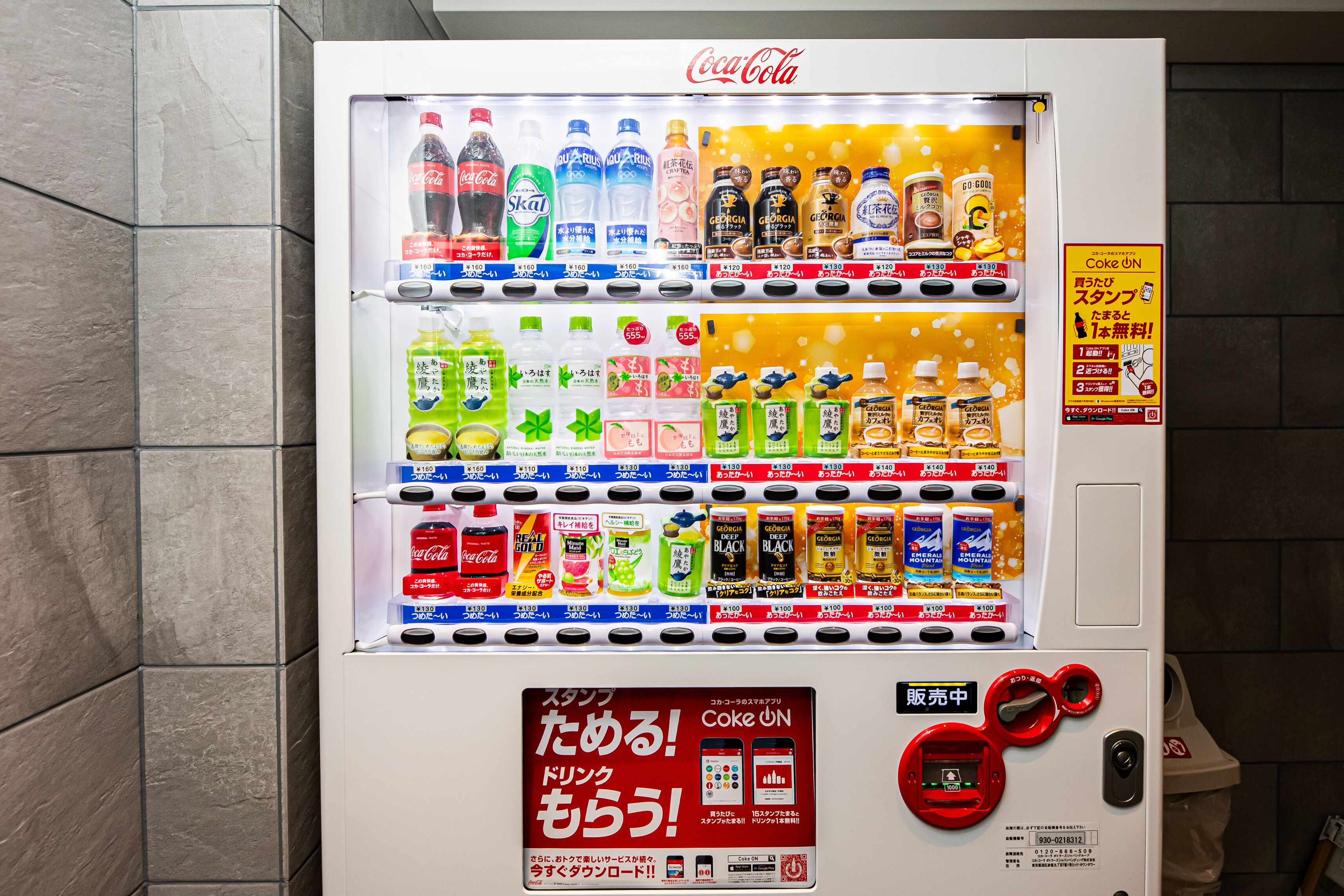 Máquina expendedora con diversas bebidas y aperitivos, incluyendo Coca-Cola y Skol, y una ranura para tarjetas de pago.