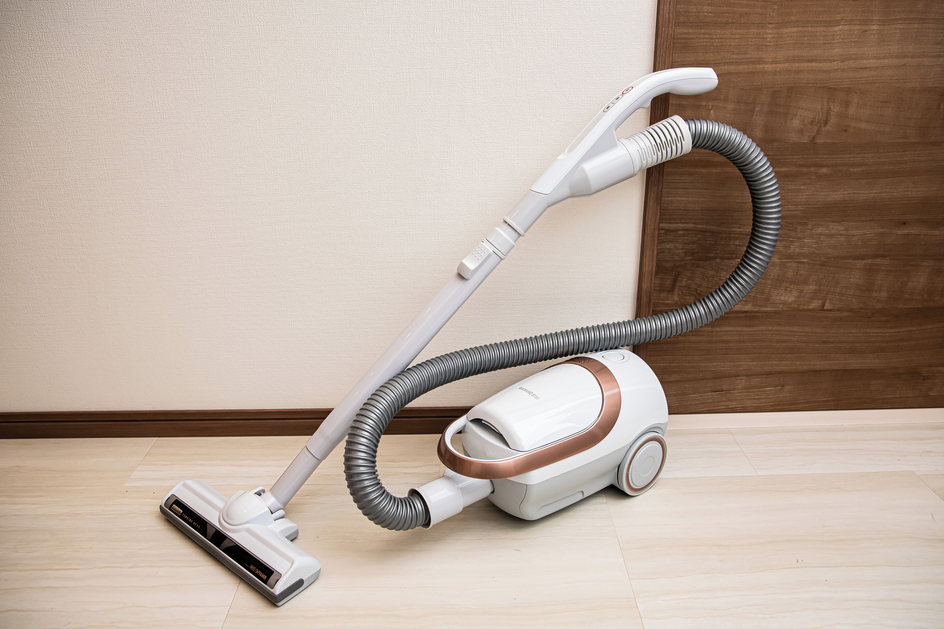 A vacuum cleaner in a room with wooden flooring and a wooden door.