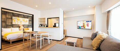 Una habitación de hotel moderna con cama, sofá, zona de comedor y cocina.