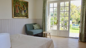 Una habitación con cama, sofá, una mesita y un ventanal con cortinas.