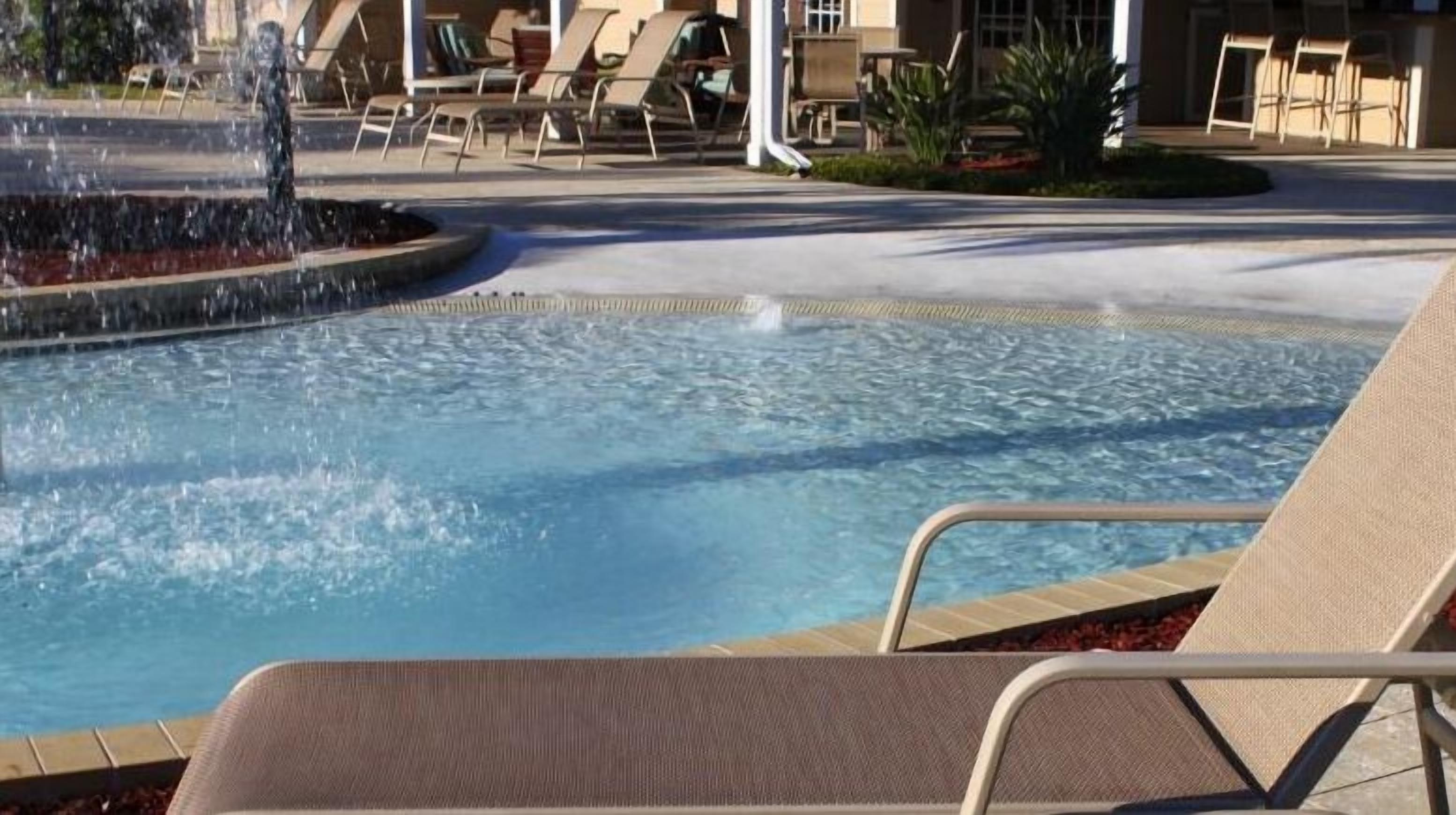 Ein Swimmingpool mit Liegestühlen und einem Wasserspiel.