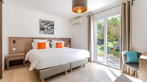 Moderni hotellihuone, jossa on suuri sänky, yöpöytä, tuoli ja näkymä ulos.
