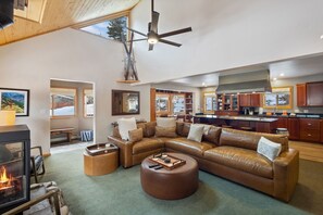 A spacious living room with a leather sofa, ottoman, and a fireplace.