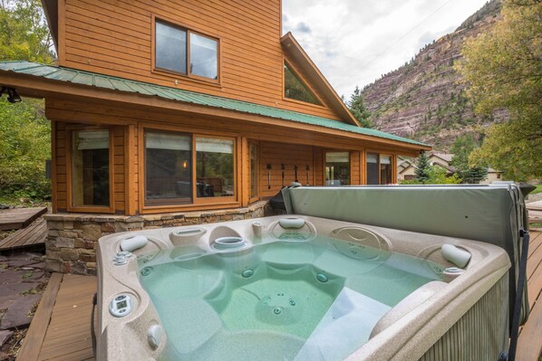 Una cabaña de madera con un jacuzzi y escalones de piedra que conducen a la entrada.