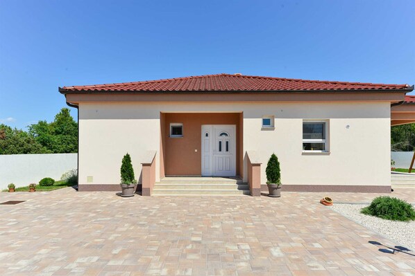 A modern two-story house with a red-tiled roof, a beige facade, and a front entrance with a white door. - Villa First Hill with heated pool (Zaton)