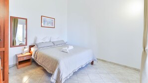 A bedroom with a bed, nightstand, and a framed picture on the wall. - Beachfront Holiday Apartment Inga Yellow with sea view (Vir)