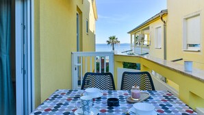 A table set with plates, cups, and a candle on a balcony with a view of the sea. - Seafront Holiday Apartment Inga Brown with sea view (Vir)