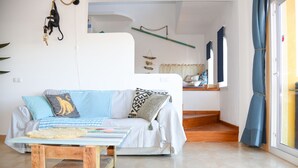 A living room with a sofa, a coffee table, and a staircase leading to a balcony.