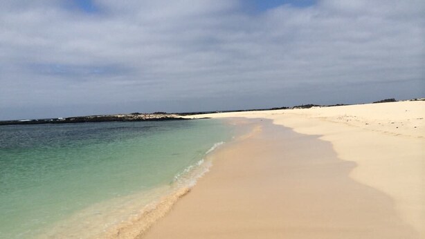 A beach with clear turquoise water and a wide sandy shore.