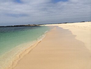 A beach with clear water and a sandy shore.
