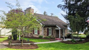 A stone house with a chimney, a front porch, and a well-maintained lawn.