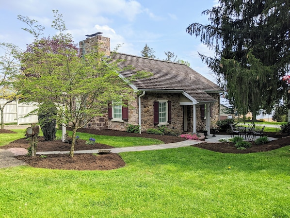 A stone house with a chimney, a front porch, and a well-maintained lawn.
