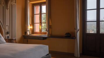 Una camera da letto con un letto, un comodino con una lampada, una finestra con tende e una porta.