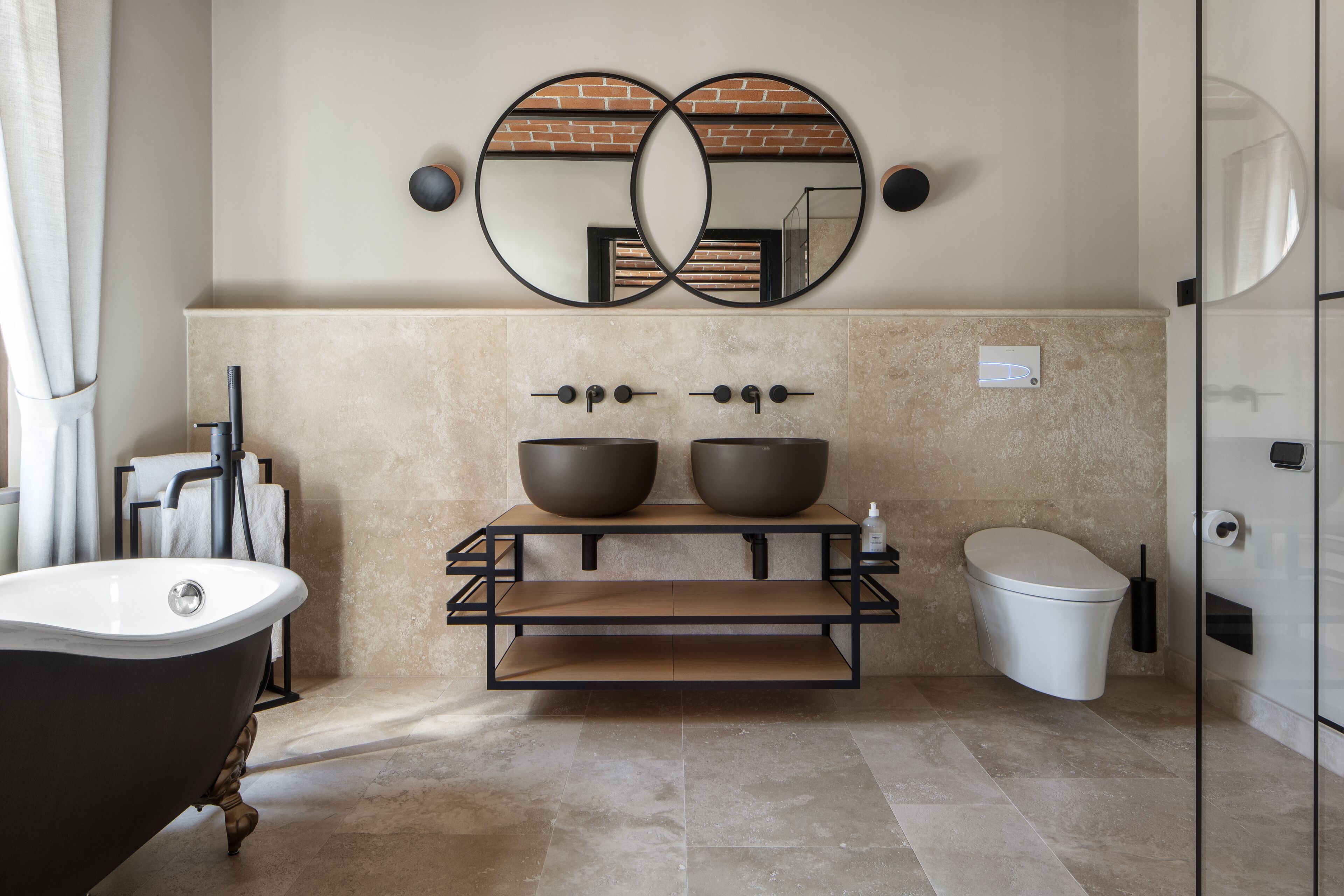 A modern bathroom with a freestanding bathtub, a double sink vanity, and a toilet.