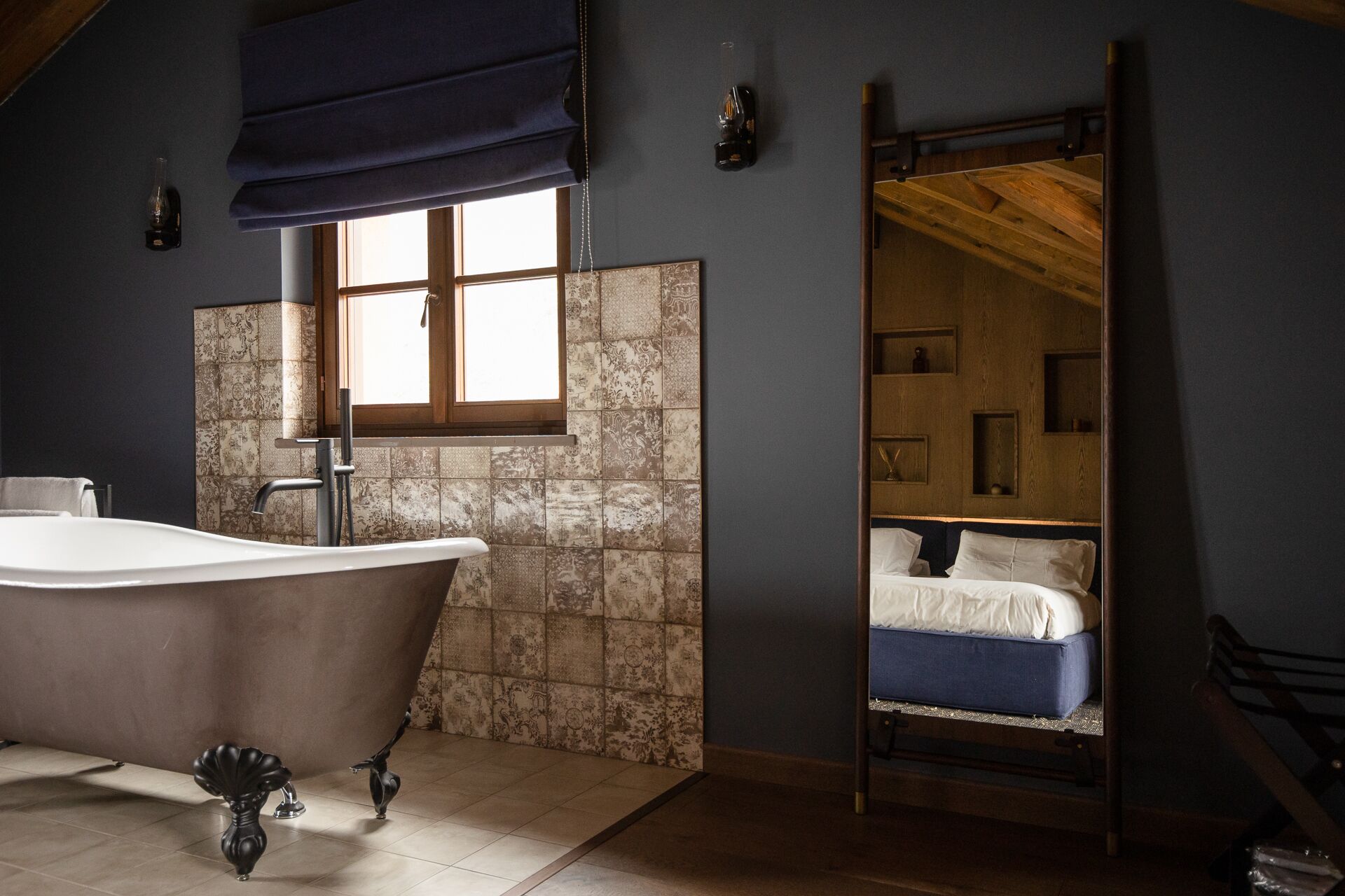 Casa de banho com banheira independente, janela com vista e escada de madeira para um espaço de dormir no mezzanino.