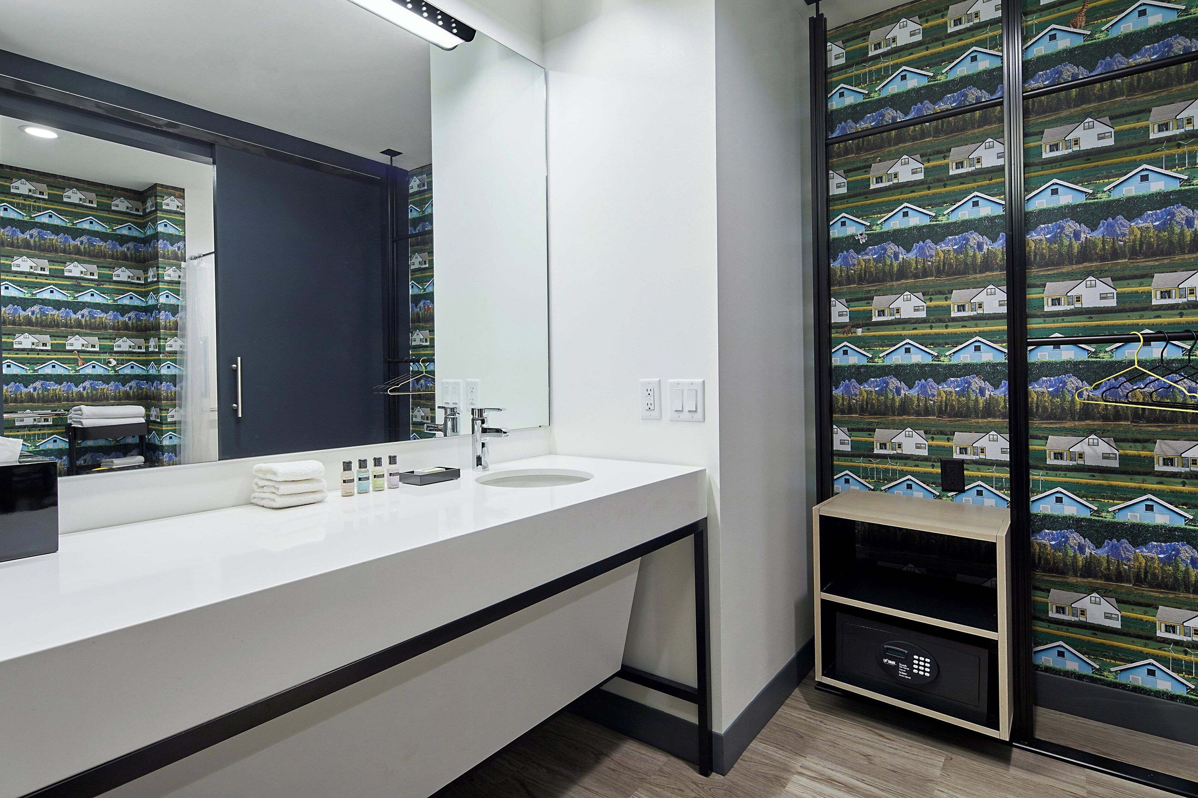 Un baño moderno con un espejo grande, un lavabo blanco y un perchero para toallas.