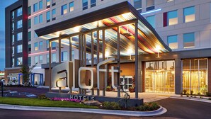 A modern hotel with a prominent 'loft' sign, large windows, and a covered entrance area. - Aloft by Marriott Chattanooga Hamilton Place (Chattanooga)