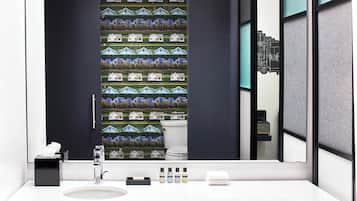 Une salle de bain avec un grand miroir, un lavabo blanc et une rangée de produits de toilette.