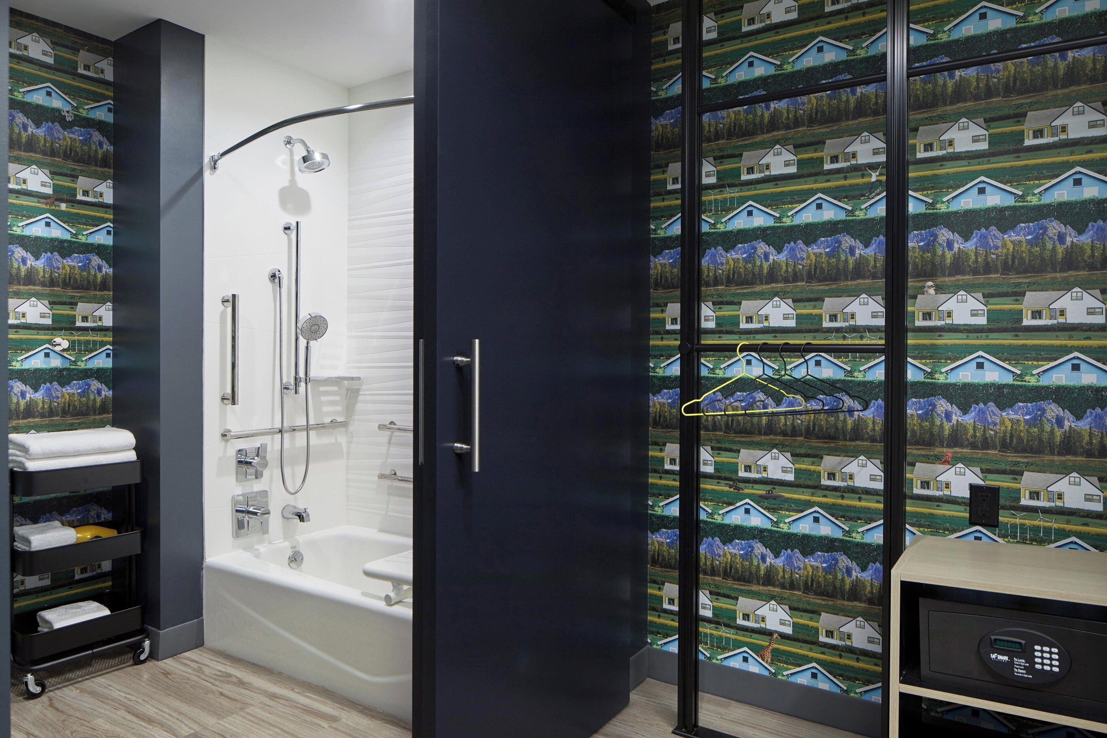 Un baño moderno con ducha envuelta en vidrio, una bañera blanca y un estante negro con toallas.