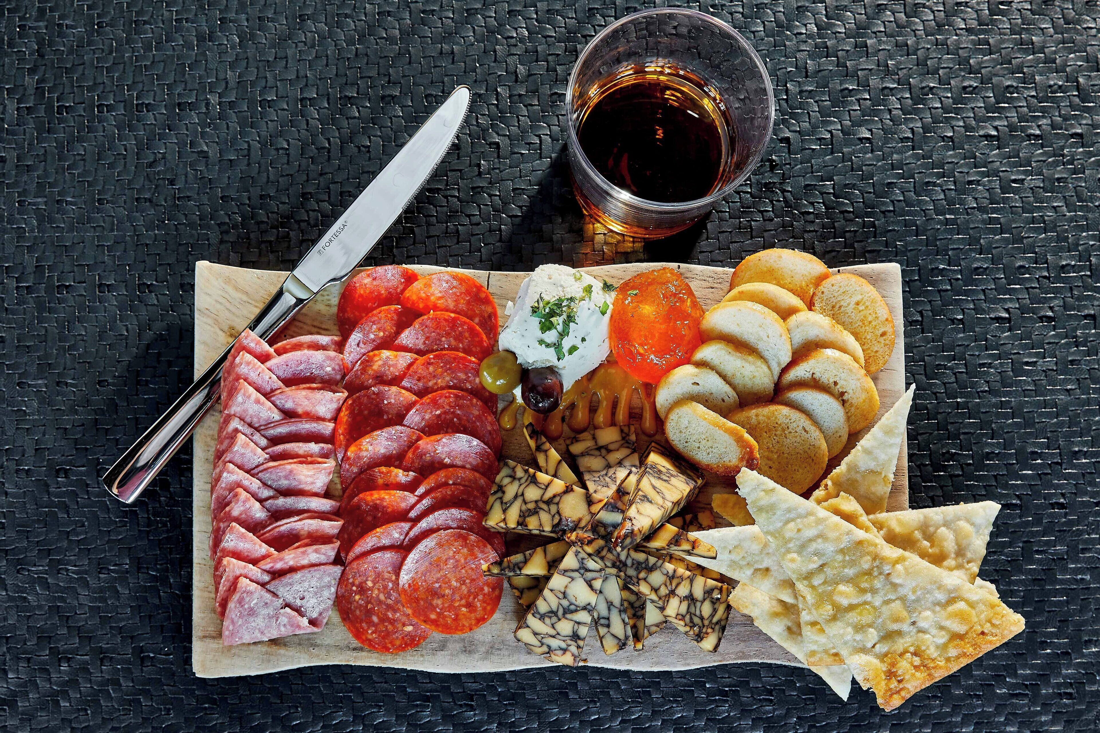 A charcuterie board with various meats, cheeses, and bread on a wooden board.