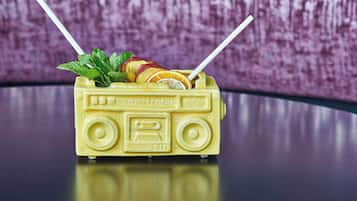 Un recipiente amarillo con forma de coche de juguete, con pajita y hojas de menta.