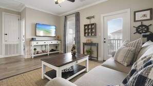 Un salon avec un ventilateur de plafond, un téléviseur, une table basse, un canapé et une cheminée.