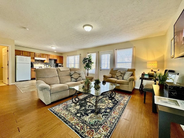 A living room with two sofas, a coffee table, a rug, and a kitchen in the background.
