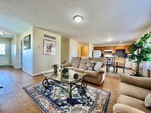A living room with a sofa, a glass coffee table, and a rug.
